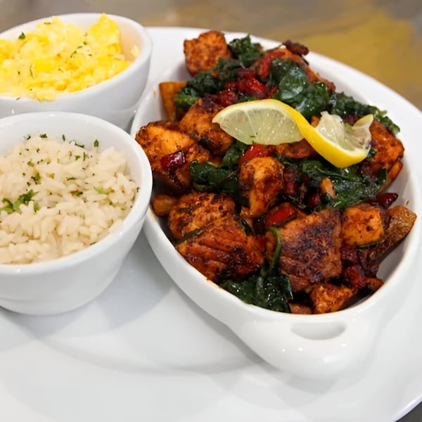 Breakfast plate with scrambled eggs, rice, and chicken with spinach and a lemon slice.