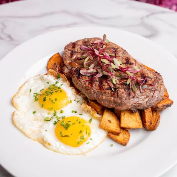Toast It IZ breakfast with grilled steak, two sunny-side-up eggs, and home fries.